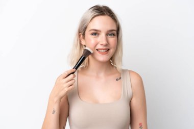 Beyaz arka planda izole edilmiş beyaz bir kadın elinde makyaj fırçası ve mutlu bir ifade var.