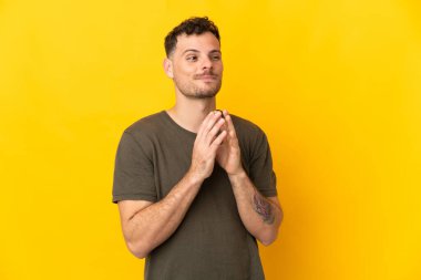 Beyaz tenli yakışıklı bir adam sarı arka planda izole edilmiş bir şeyler çeviriyor.