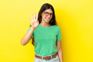 Sarı arka planda izole edilmiş genç beyaz kadın mutlu ve parmakları olan dört kişi sayıyor.
