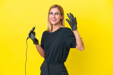 Dövmeci Uruguaylı kadın, sarı arka planda izole edilmiş, mutlu bir ifadeyle selamlıyor.