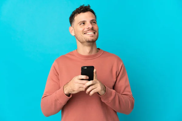 Junger Kaukasischer Gutaussehender Mann Isoliert Auf Blauem Hintergrund Mit Handy — Stockfoto