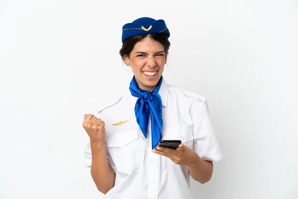 비행기의 스튜워디스 카시아 여자가 배경에 고립되어 승리의 위치에 핸드폰을 가지고 — 스톡 사진