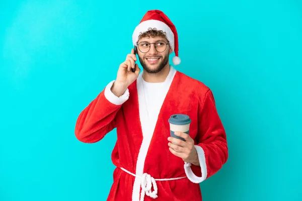 Joven Disfrazado Santa Claus Aislado Sobre Fondo Azul Sosteniendo Café —  Fotos de Stock