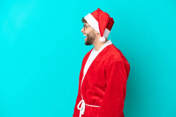 Молодой Человек Замаскированный Санта Клауса Синем Фоне Смеется Боковом Положении — стоковое фото