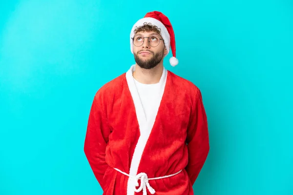 Ung Man Förklädd Till Jultomten Isolerad Blå Bakgrund Och Tittar — Stockfoto