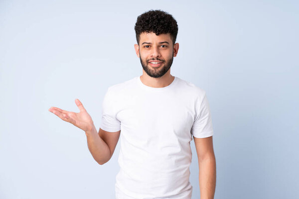 Молодой марокканский человек, изолированный на синем фоне, делает жесты сомнений