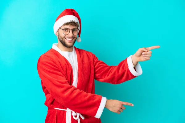 Jongeman Vermomd Als Kerstman Geïsoleerd Blauwe Achtergrond Wijzende Vinger Naar — Stockfoto