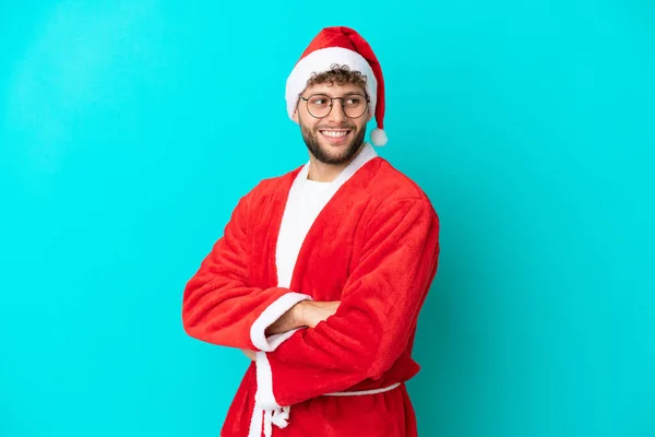 Ung Man Förklädd Till Jultomten Isolerad Blå Bakgrund Med Armarna — Stockfoto