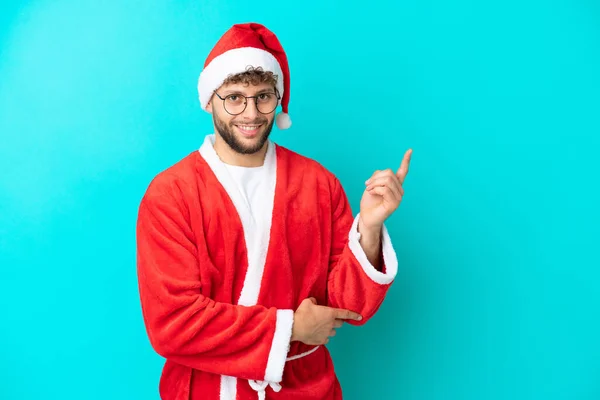 Mladý Muž Přestrojený Santa Clause Izolovaný Modrém Pozadí Ukazující Prstem — Stock fotografie