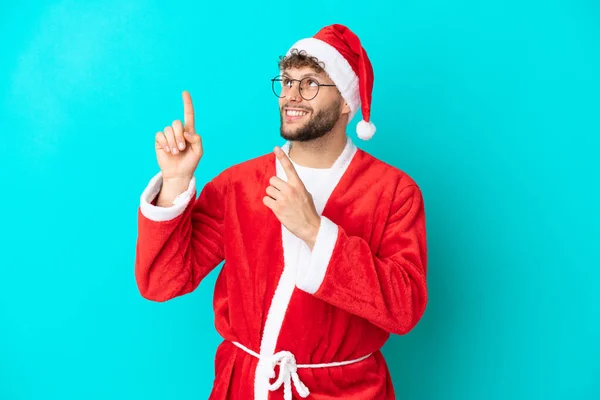 Mladý Muž Převlečený Santa Clause Izolovaný Modrém Pozadí Ukazuje Ukazováčkem — Stock fotografie