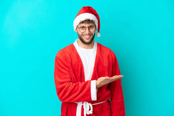 Joven Disfrazado Santa Claus Aislado Sobre Fondo Azul Presentando Una —  Fotos de Stock
