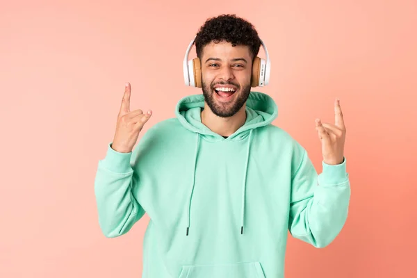 Joven Marroquí Aislado Sobre Fondo Rosa Escuchando Música Haciendo Gestos — Foto de Stock