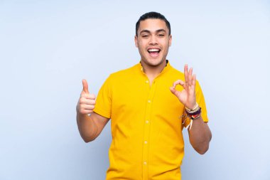 Asyalı yakışıklı adam izole edilmiş arka planda tamam işareti ve işaret işareti gösteriyor.