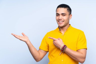 Asyalı yakışıklı, izole edilmiş arka plan üzerinde. Avucunun içine reklam koymak için hayali bir alan tutuyor.