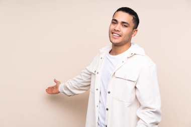 Asyalı yakışıklı adam soyutlanmış arka planda. Davet edilmek için ellerini yana uzatıyor.