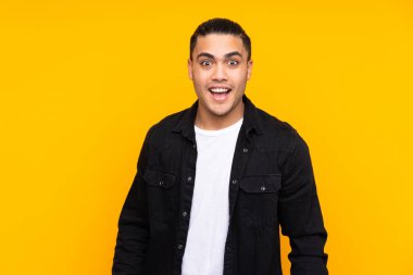 Asyalı yakışıklı adam sarı arka planda izole edilmiş. Durma hareketi yapıyor ve yüzünü kapatıyor.
