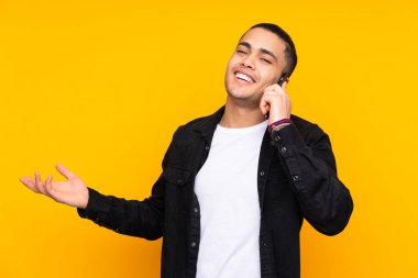 Asyalı yakışıklı adam sarı arka planda izole edilmiş, ağzı elleriyle kapatıyor.