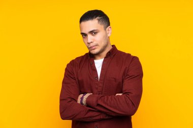 Asyalı yakışıklı adam sarı arka planda şüpheli hareketler yapıyor.