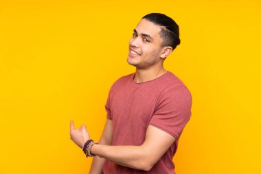 Asyalı yakışıklı adam sarı arka planda izole edilmiş para hareketi yapıyor ama mahvolmuş.