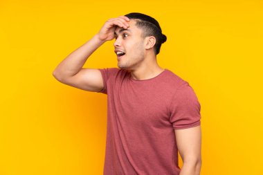 Asyalı yakışıklı adam sarı arka planda izole edilmiş, şaşırmış ve bir mesaj gönderiyor.