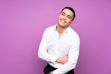 Asyalı yakışıklı adam mavi arka planda yalnız gülüyor.