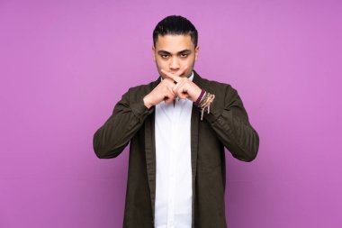 Asyalı yakışıklı adam mavi arka planda izole edilmiş sessizlik işareti gösteriyor.