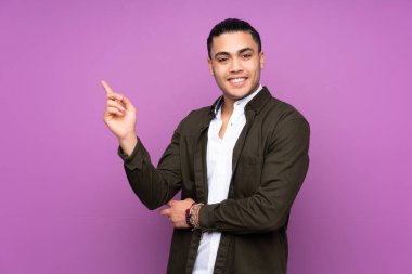 Asyalı yakışıklı adam mavi arka planda izole edilmiş mutlu ve yukarıya bakıyor.