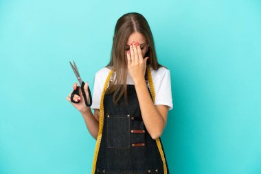 Genç Litvanyalı terzi kadın yorgun ve hasta bir ifadeyle mavi arka planda izole edilmiş.