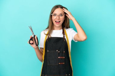 Genç Litvanyalı terzi kadın mavi arka planda izole edilmiş, sürpriz bir ifadeyle.