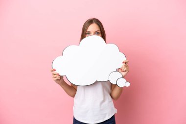 Genç Litvanyalı bir kadın pembe arka planda izole edilmiş bir konuşma balonu tutuyor ve arkasında saklanıyor.