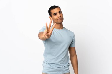 İzole edilmiş beyaz arka planı olan Afrikalı Amerikalı adam mutlu ve parmaklarıyla üçe kadar sayıyor.