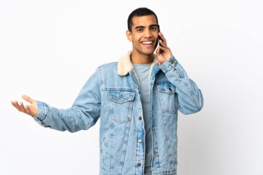 İzole edilmiş beyaz arka planı olan Afrikalı Amerikalı bir adam cep telefonuyla sohbet ediyor.
