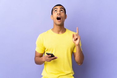 İzole edilmiş mor arka plan üzerinde işaret parmağıyla işaret eden Afro-Amerikalı bir adam. Harika bir fikir.