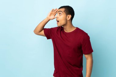 Afro-Amerikalı erkek, yalıtılmış arka planda sürpriz bir ifadeyle yan yana bakarken