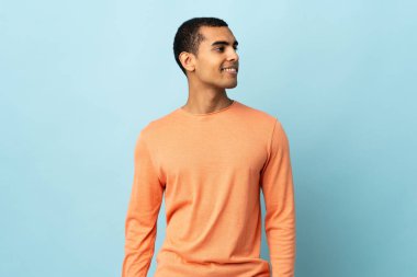 Afrikalı Amerikalı bir adam izole edilmiş arka planda, yana bakıyor ve gülümsüyor.