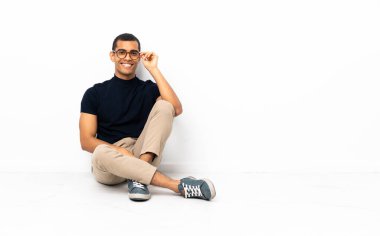 Afro-Amerikalı adam yerde oturuyor, gözlüklü ve mutlu.