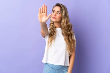 Mor arka planda izole edilmiş genç Brezilyalı kadın dur hareketi yapıyor ve hayal kırıklığına uğruyor