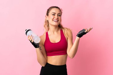 Pembe arka planda izole edilmiş genç Brezilyalı kadın spor su şişesiyle