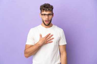 Mor arka planda izole edilmiş beyaz adam sağa bakarken şaşırmış ve şok olmuş.