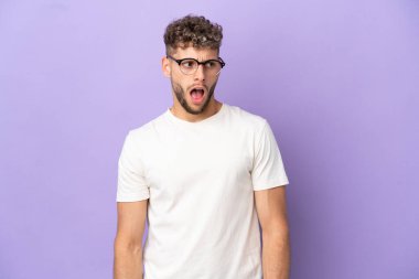 Teslimat yapan beyaz adam mor arka planda izole edilmiş. Yan tarafa bakarken sürpriz jest yapıyor.