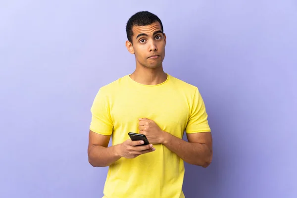 Hombre Afroamericano Sobre Fondo Púrpura Aislado Usando Teléfono Móvil Suplicando —  Fotos de Stock