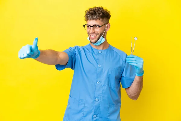 Dentist Blonde Man Holding Tools Isolated Background Giving Thumbs Gesture — 图库照片