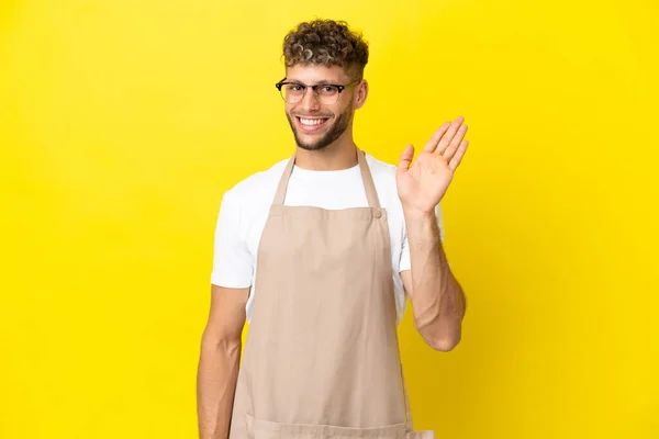 Restauracja Kelner Blondynka Człowiek Izolowany Żółtym Tle Salutowanie Ręki Happy — Zdjęcie stockowe