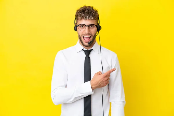 Telemarketer Blondynka Człowiek Pracuje Słuchawki Izolowane Żółtym Tle Zaskoczony Wskazując — Zdjęcie stockowe