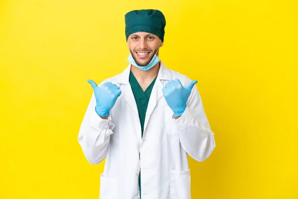 Cirurgião Loiro Homem Uniforme Verde Isolado Fundo Amarelo Com Polegares — Fotografia de Stock