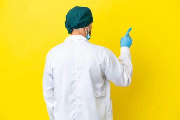 Χειρούργος Ξανθός Άνδρας Πράσινη Στολή Απομονωμένος Κίτρινο Φόντο Που Δείχνει — Φωτογραφία Αρχείου
