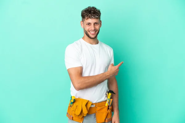 stock image Young electrician blonde man isolated on green background pointing back