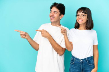 Genç melez çift mavi arka planda izole edildi.