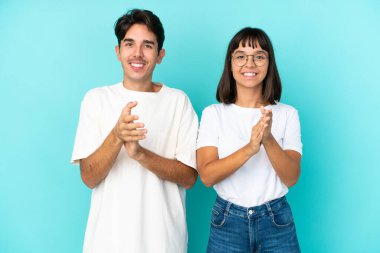 Genç melez çift mavi arka planda bir konferansta sunumdan sonra alkış tutuyorlar.