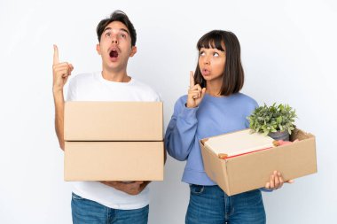Genç bir çift, beyaz arka planda izole edilmiş şeylerle dolu bir kutuyu seçerken bir fikri işaret ederek hareket ediyor.